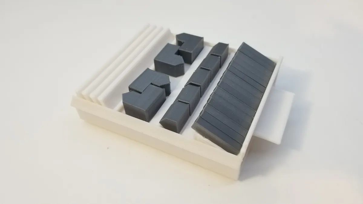 A compact white printed case with fitted spaces for gray roads, settlements, and cities.
