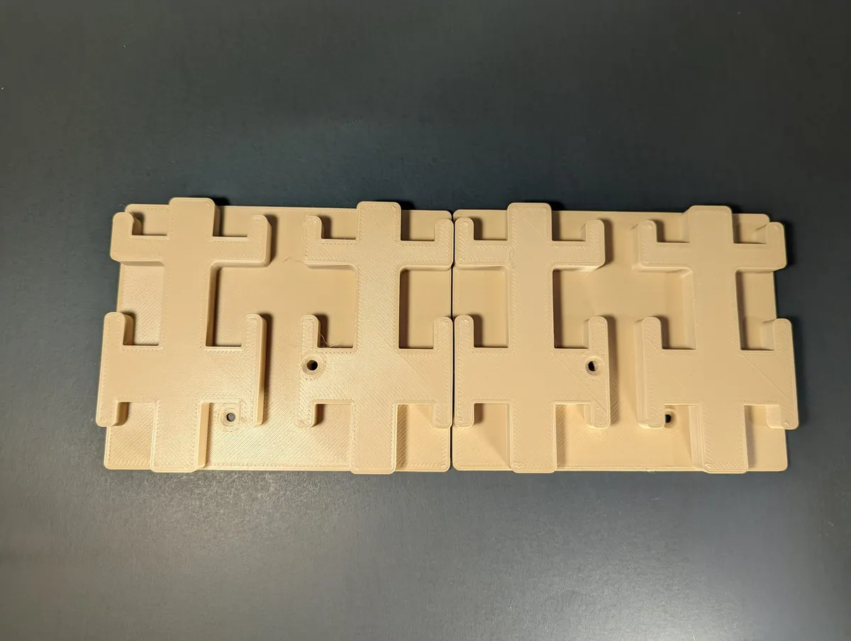 Two cream printed four-slot holder blocks lying side by side on a dark surface.