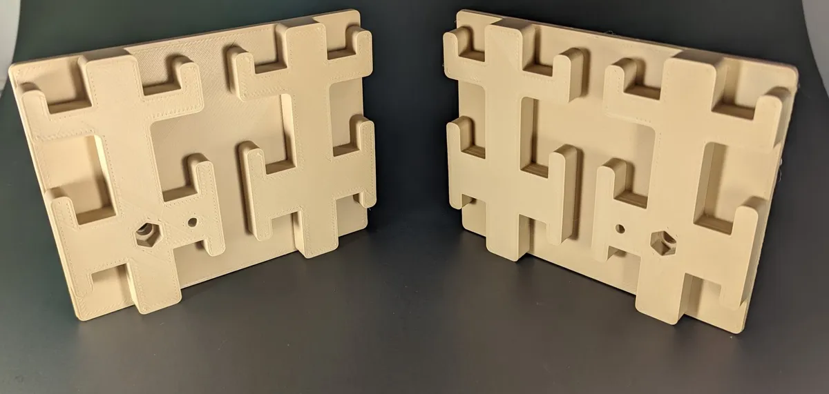 Two cream four-slot holder blocks standing upright facing each other on a dark surface, with screw holes visible.