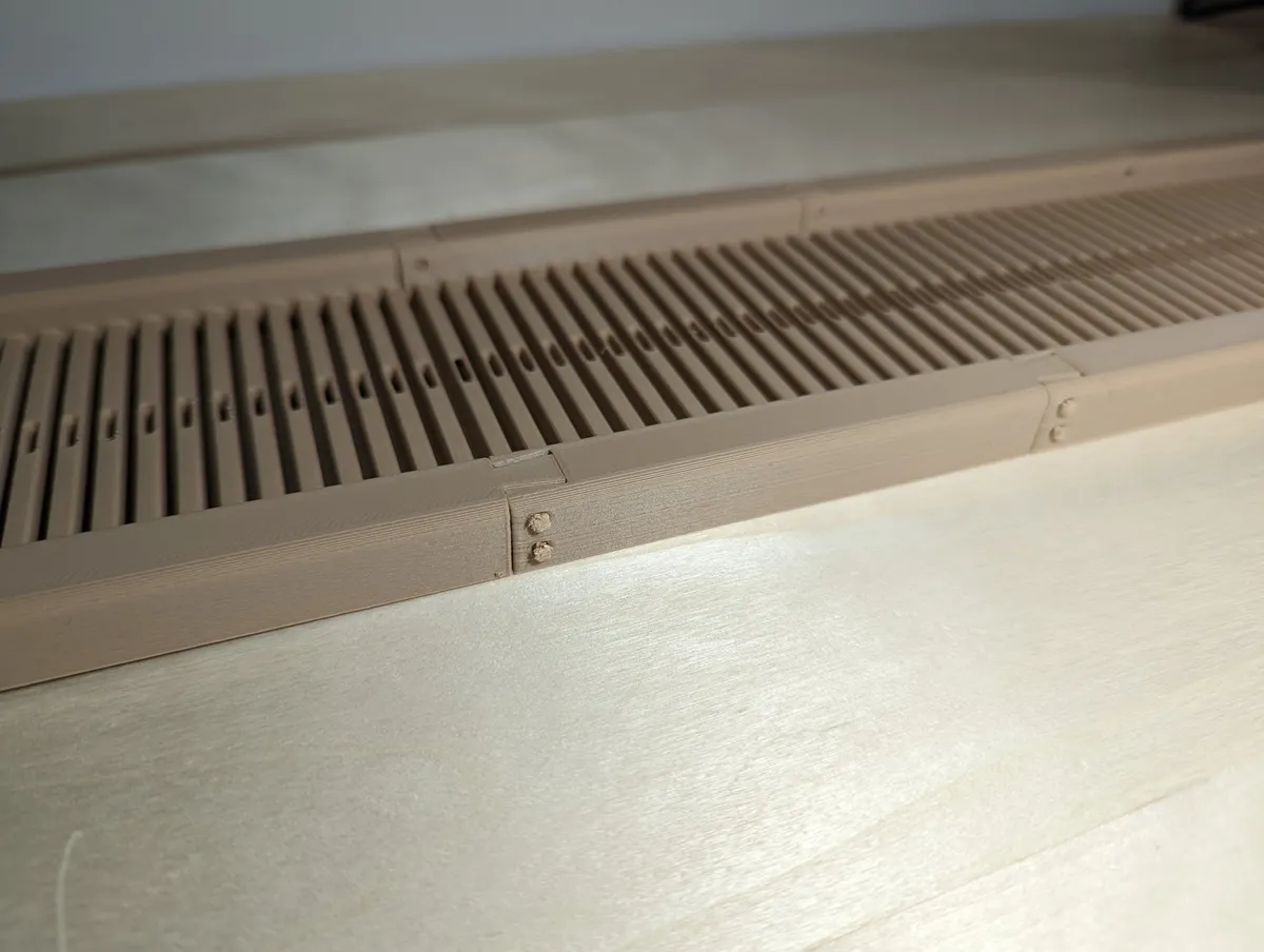 A low-angle close-up looking along the repeated slots and holes of a long assembled printed reed.