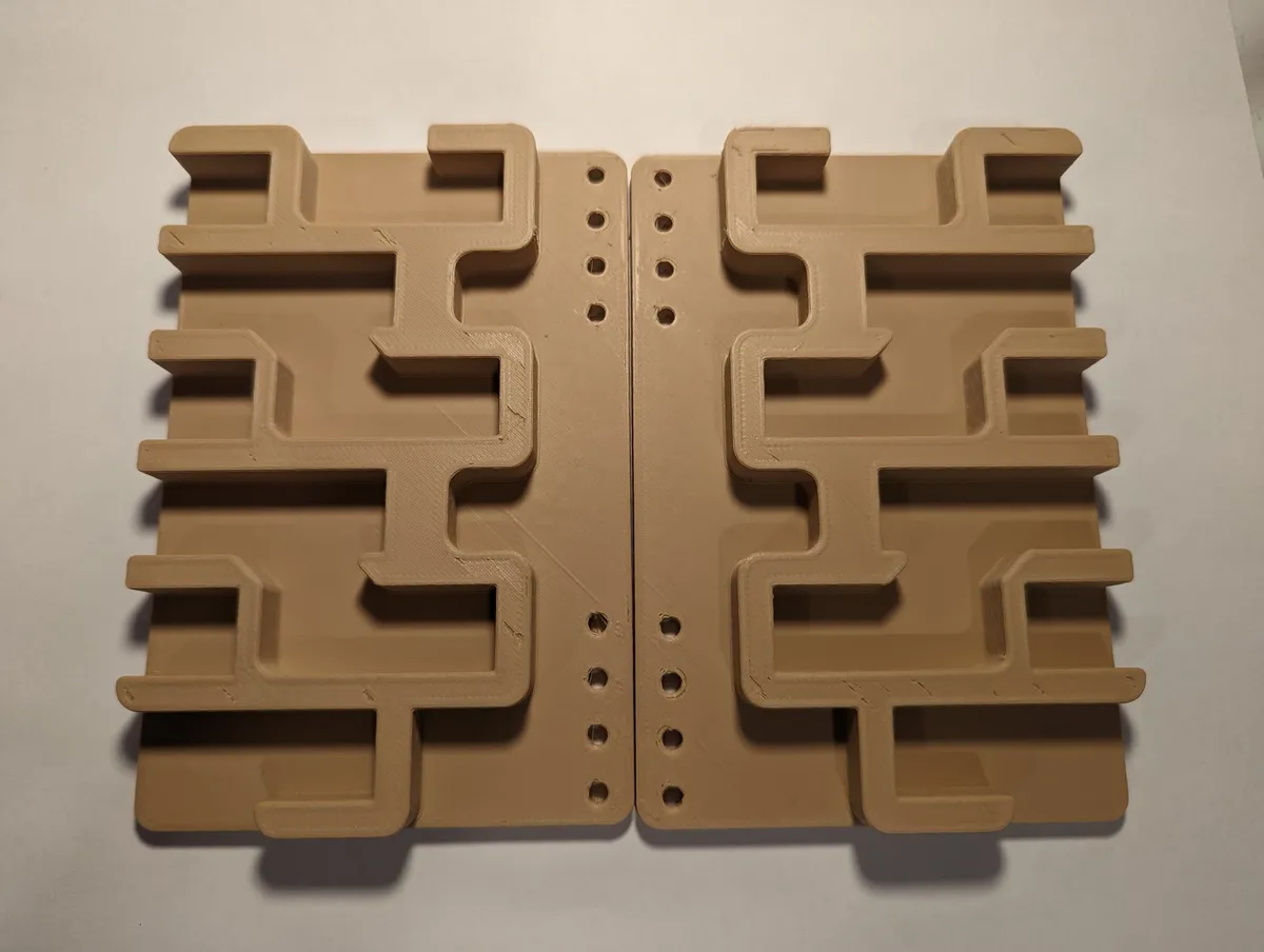 A mirrored pair of flat tan printed panels, each with three stepped rows of hook-shaped slots and mounting holes along the inner edge.
