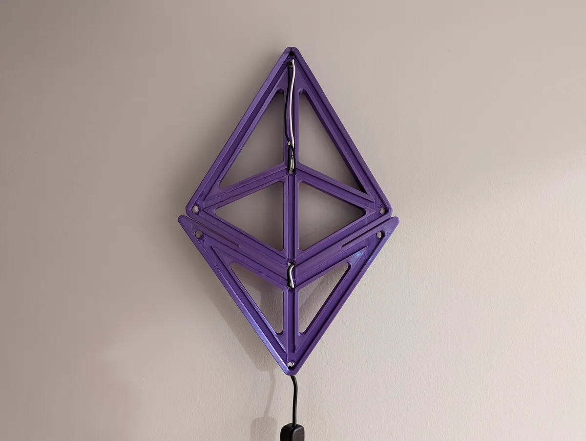 The unlit purple geometric light frame mounted on a wall, showing its channels and support structure.