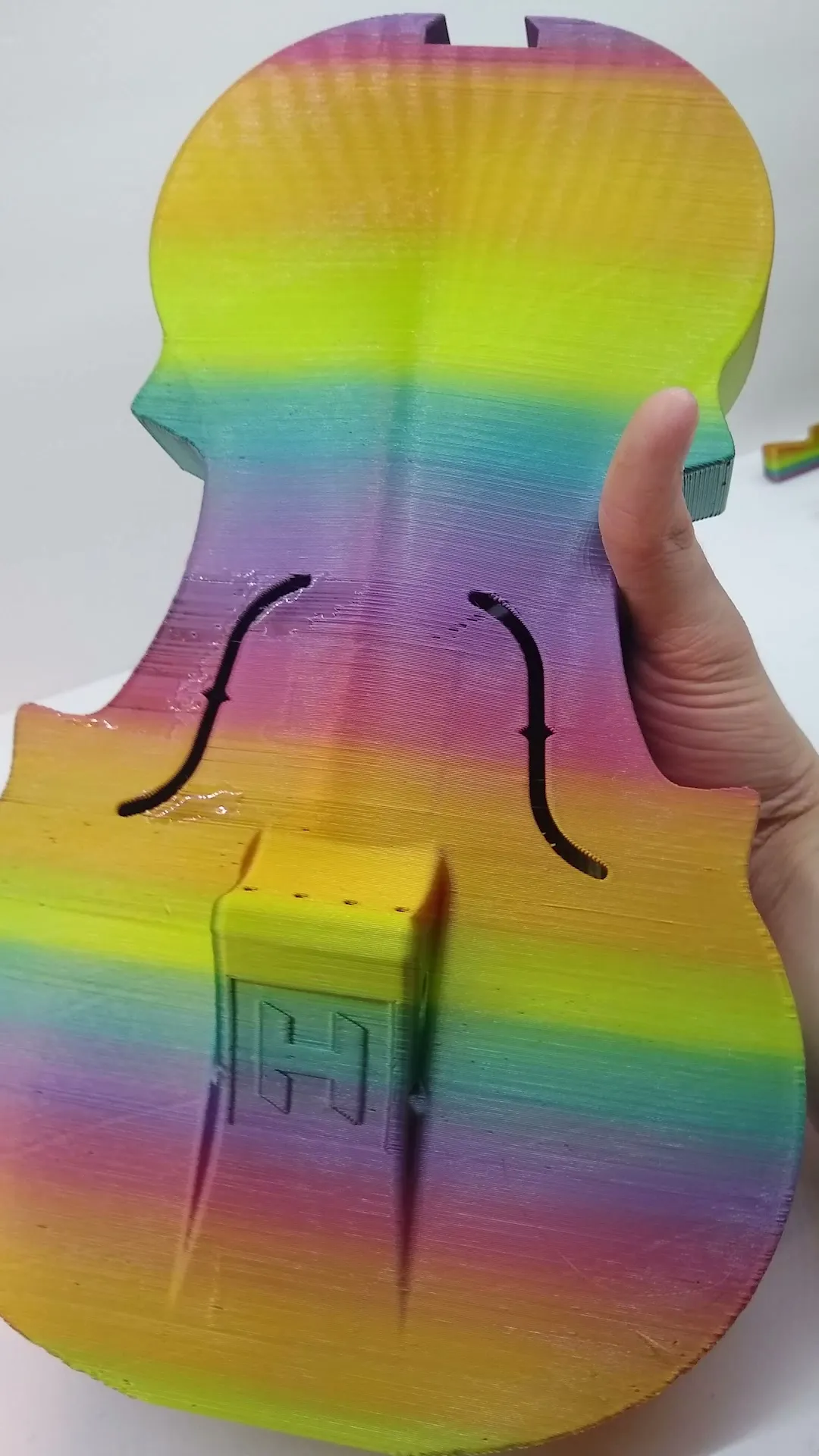 The completed rainbow violin body held upright before fitting the neck, bridge, and strings.
