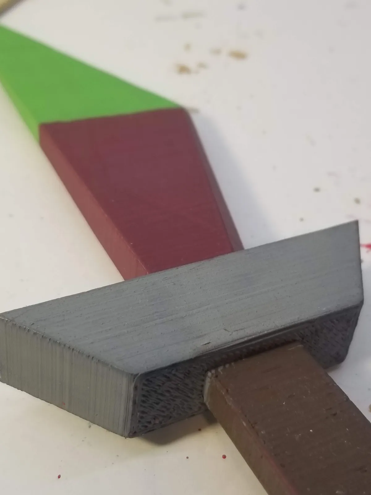 Close view of a hand-painted dagger prop with a red blade, green tip, gray guard, and brown handle.