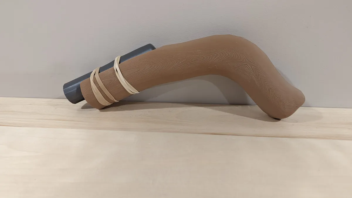 A small Eoka display replica with a tan curved handle, dark barrel, and wrapped detail.