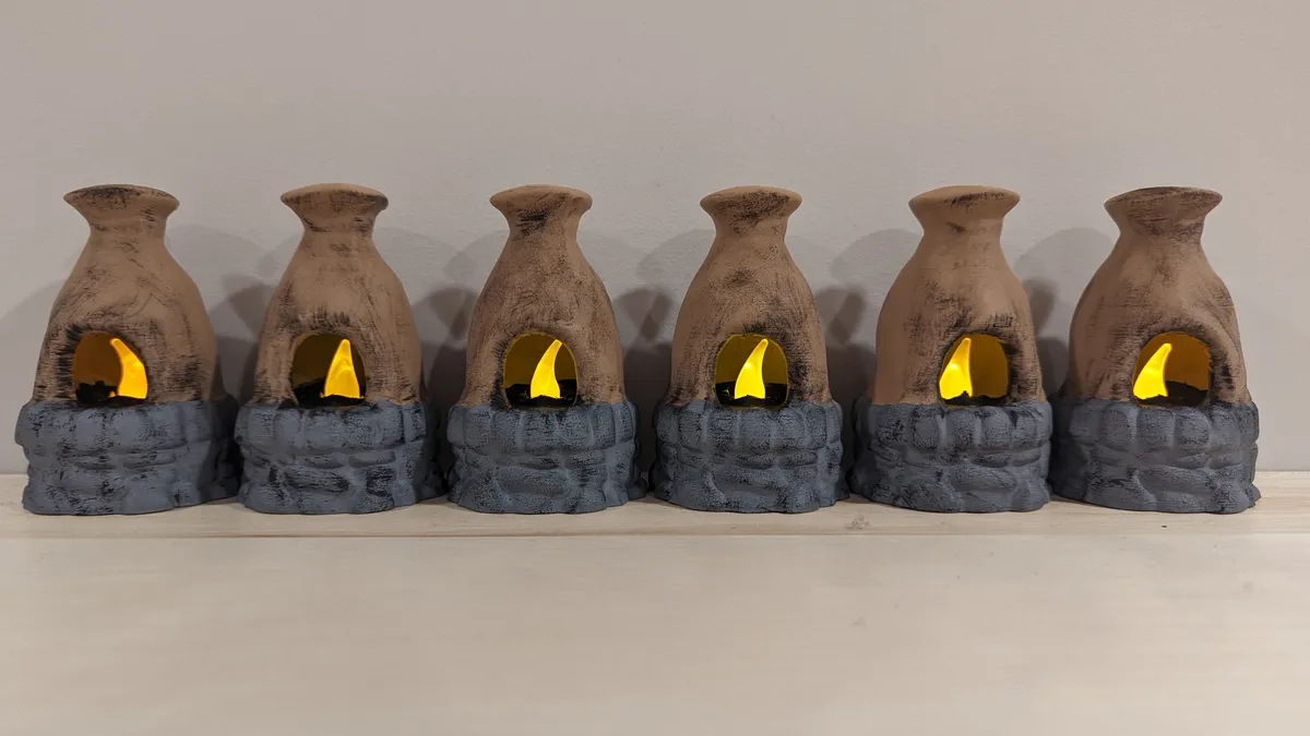 Six hand-painted miniature furnaces with tan tops, gray stone bases, and glowing yellow interiors.