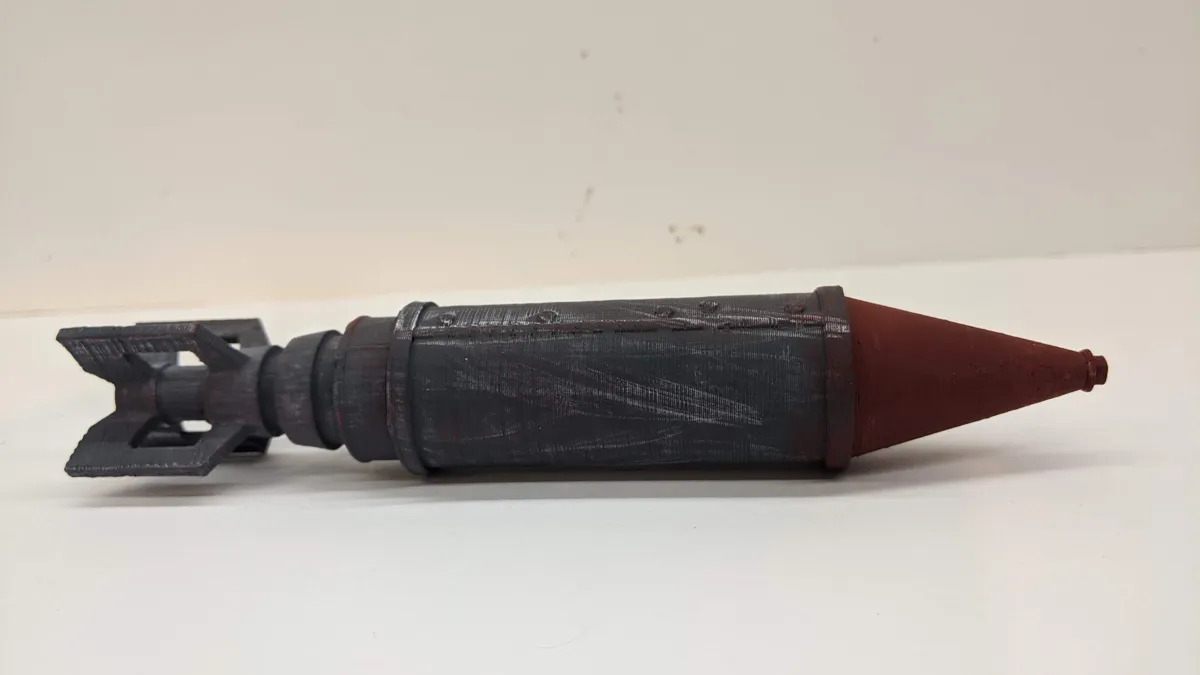 A painted miniature rocket display prop with a dark body, red tip, and open tail details.